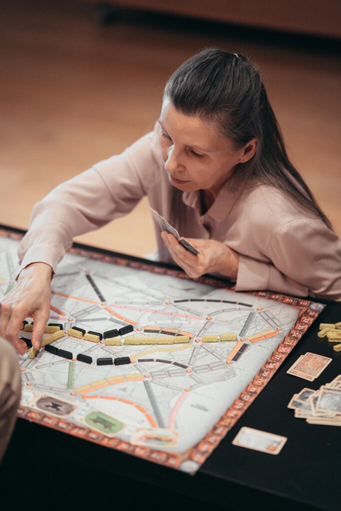 Elderly woman playing a board game, focusing on strategy indoors.