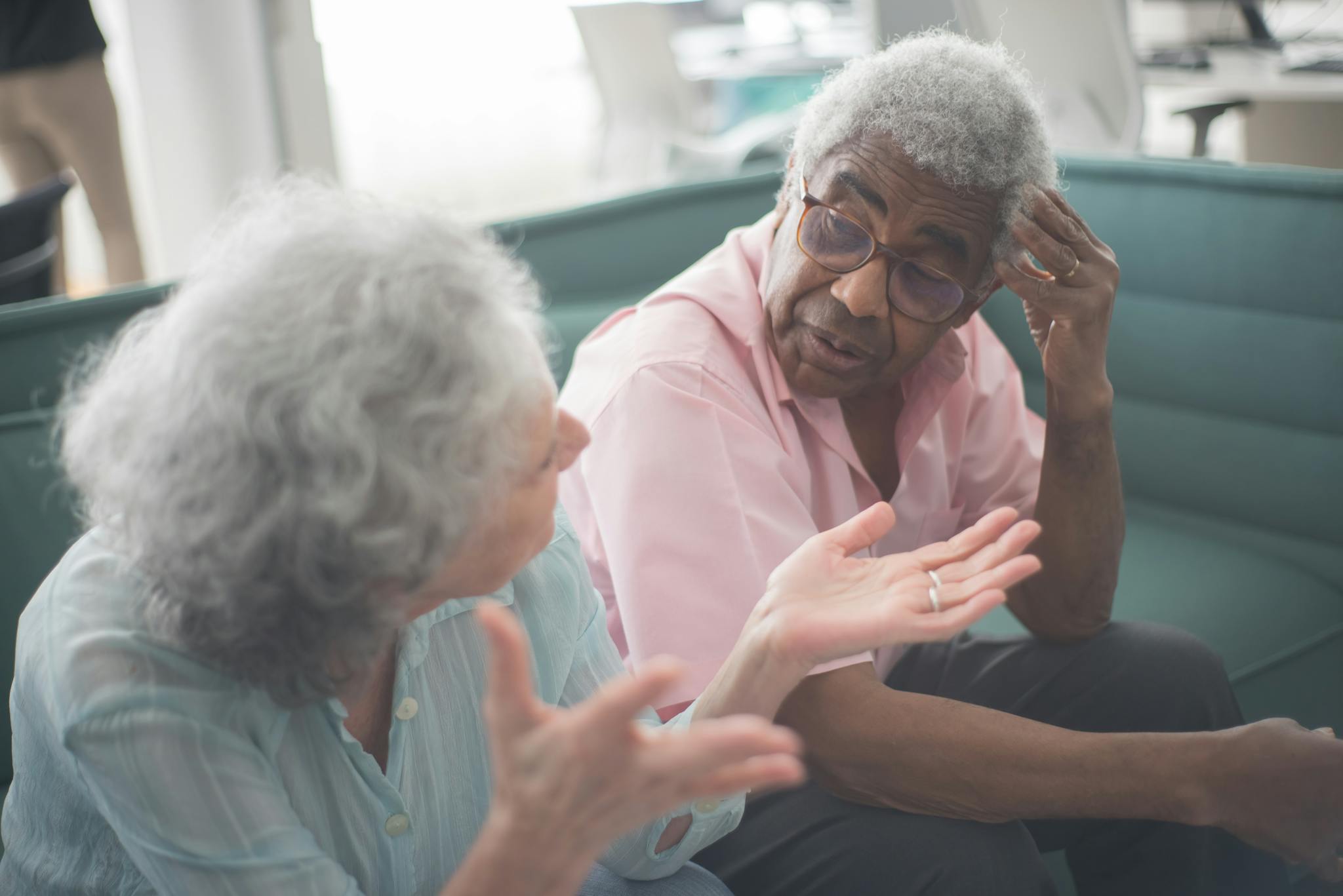 Two senior adults having a thoughtful discussion on a comfortable couch indoors.
